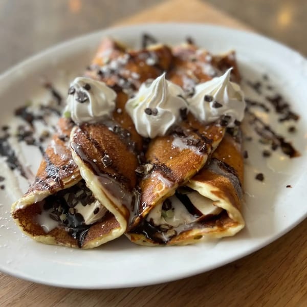 Sassy Onion's crepes filled with cream, drizzled with chocolate sauce, and topped with whipped cream.